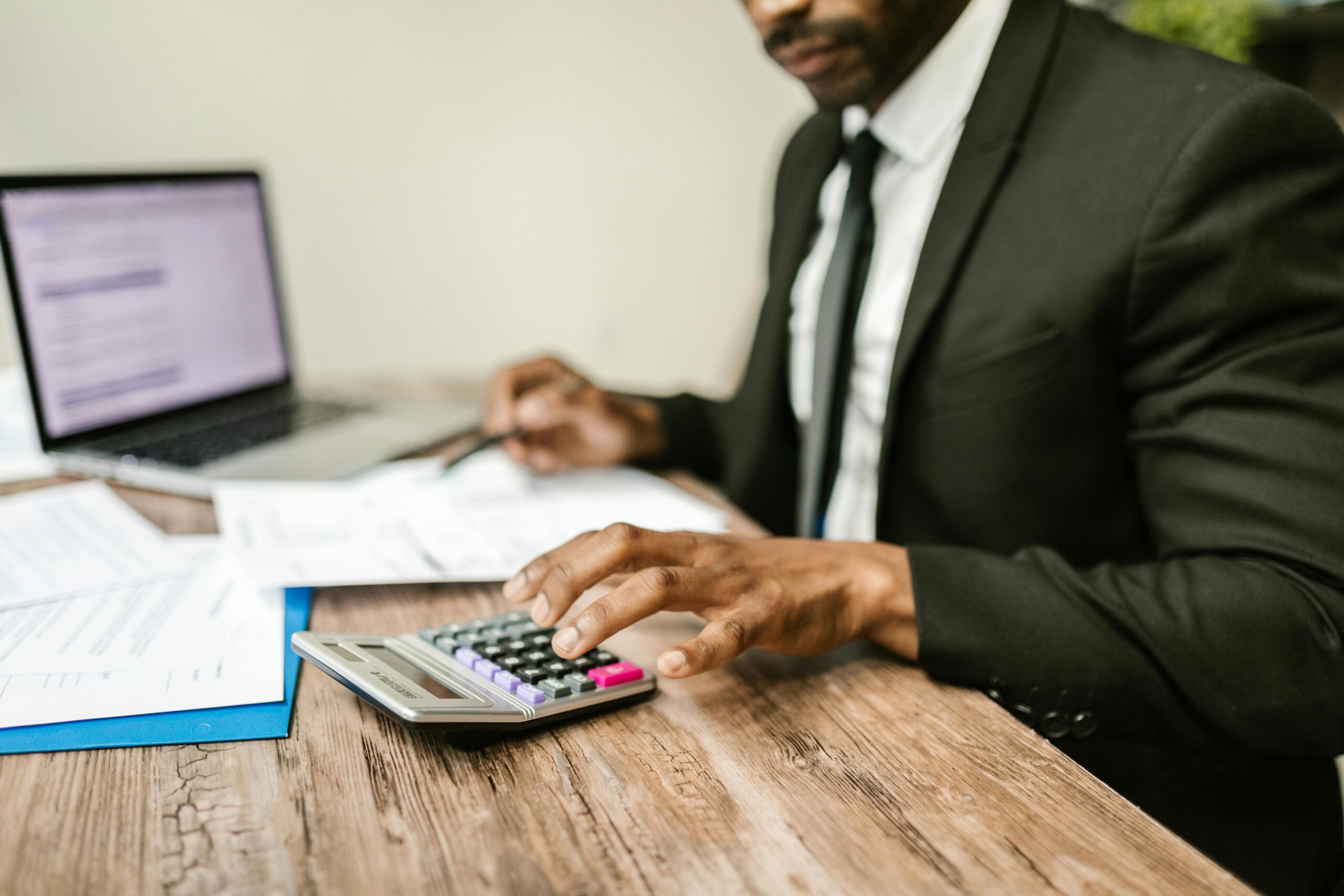 Fractional CFO typing into calculator at desk while on computer