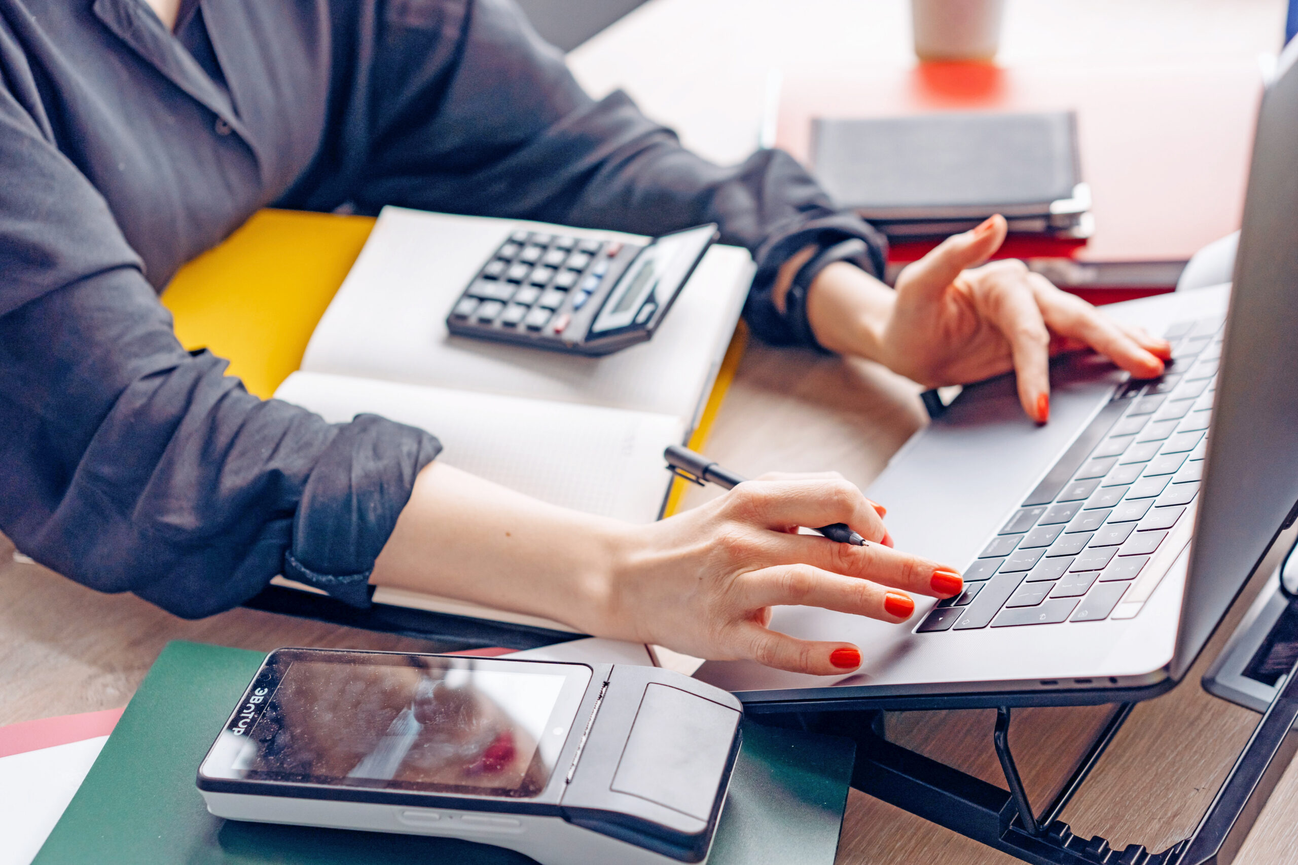 person at desk with computer, books, and calculator, the importance of bookkeeping for small business, keeping things clean
